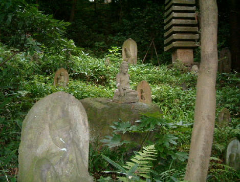 仏像・門・地蔵が多数配置された自然庭園の風景